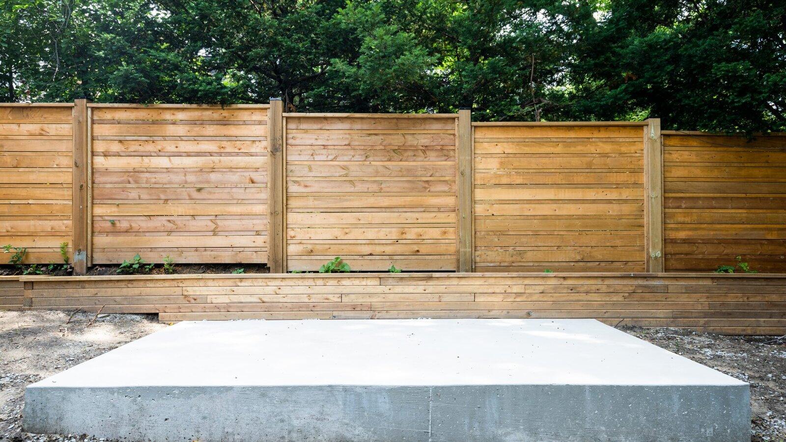 Poured concrete pad with privacy fence and retaining wall in The Kingsway